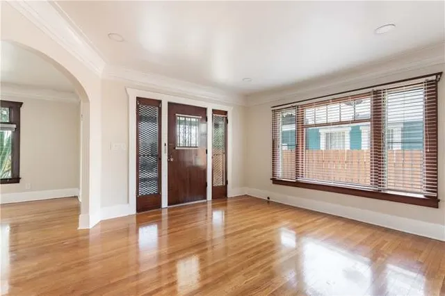 an empty room with wooden floor and windows