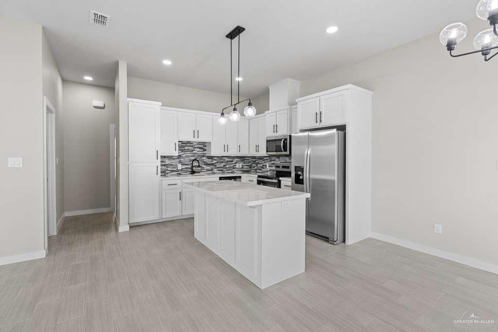 3501 Kerps Street Weslaco, TX 78599 - Photo 3 of 12 a kitchen with white cabinets and stainless steel appliances