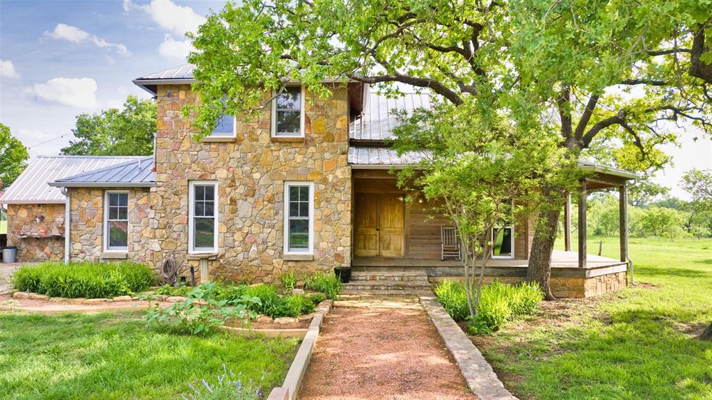 2969 County Lane Talpa, TX 76882 - Photo 2 of 40 Stone-clad residence featuring a metal roof and a covered front porch with supporting columns