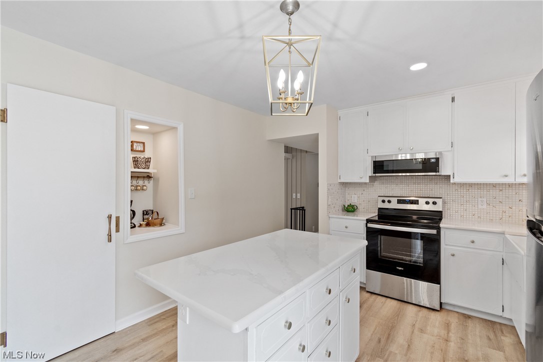 203 Pontius Road Mogadore, OH 44260 - Photo 13 of 26 Kitchen with a center island, light hardwood flooring, white cabinetry, hanging light fixtures, and appliances with stainless steel finishes