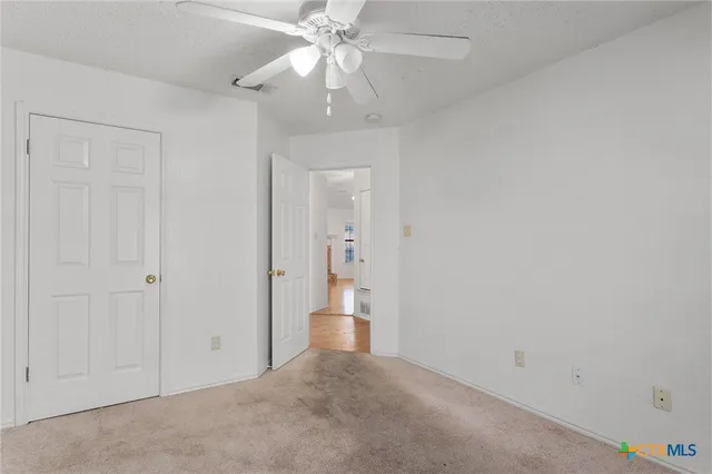 an empty room with a bathroom and a chandelier fan