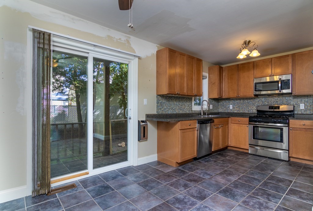 38 Farmland Road, Unit A Lowell, MA 01850 - Photo 6 of 26 a kitchen with granite countertop a stove a sink and a refrigerator