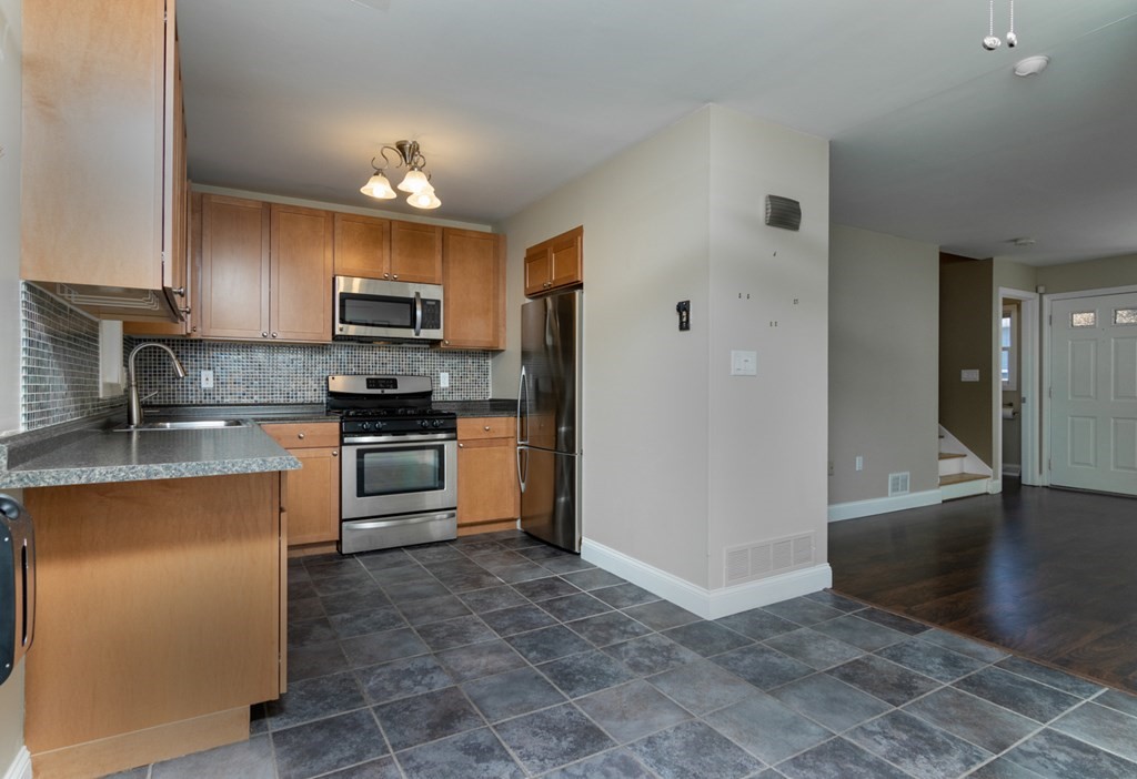38 Farmland Road, Unit A Lowell, MA 01850 - Photo 7 of 26 a kitchen with kitchen island a counter top space a sink stainless steel appliances and cabinets