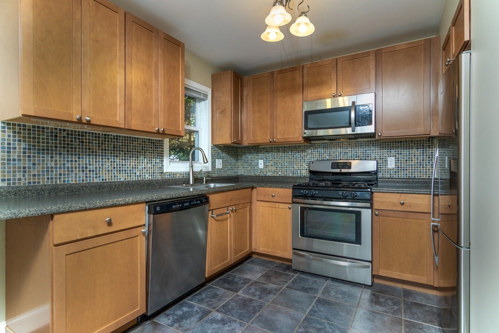 38 Farmland Road, Unit A Lowell, MA 01850 - Photo 8 of 26 a kitchen with stainless steel appliances granite countertop a stove a sink and a microwave