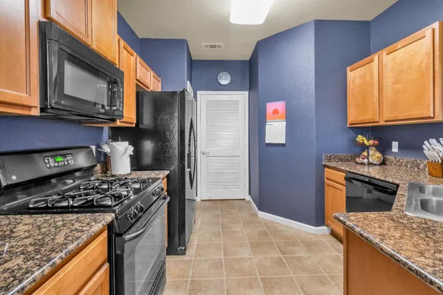 a kitchen with stainless steel appliances granite countertop a stove a sink and a refrigerator