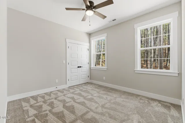 an empty room with windows and fan