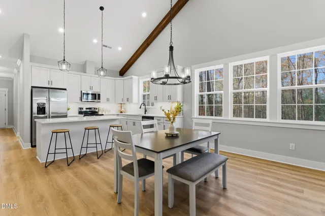 a kitchen with stainless steel appliances kitchen island granite countertop a table chairs and a wooden floor
