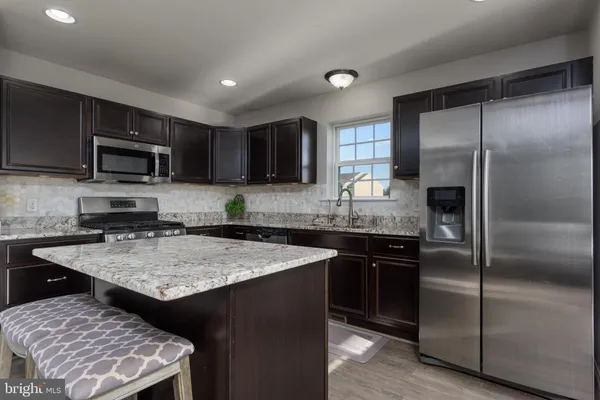 a kitchen with stainless steel appliances granite countertop a refrigerator a sink a stove a microwave and wooden cabinets