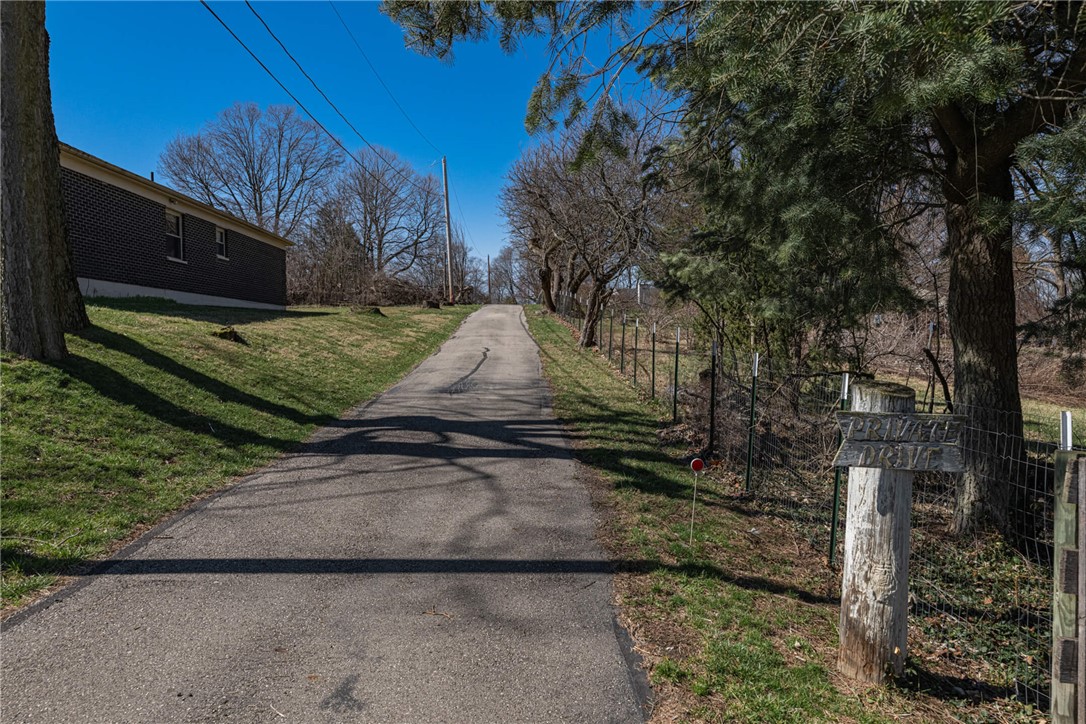 6885 Garber Road Clayton, OH 45415 - Photo 24 of 24 A long, winding driveway leads up to a secluded property, surrounded by lush trees and greenery.