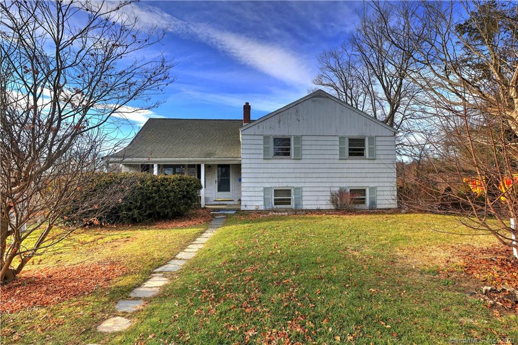 a front view of house with yard and trees in the background