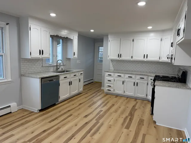 a kitchen with stainless steel appliances granite countertop a refrigerator a stove and white cabinets