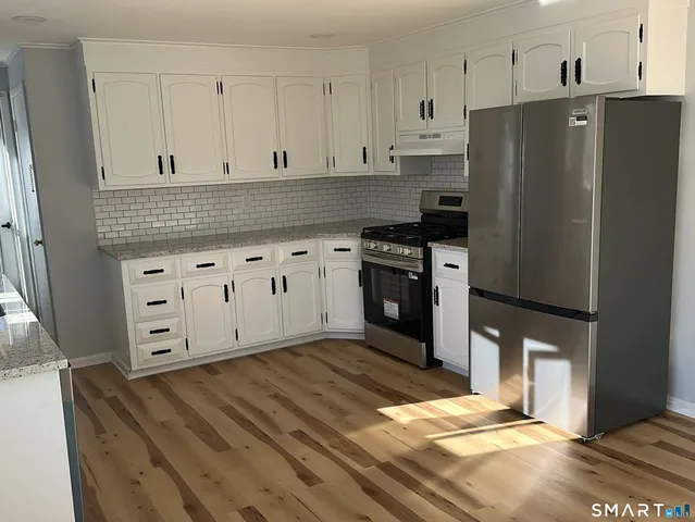 a kitchen with stainless steel appliances wooden floor sink and wooden cabinets