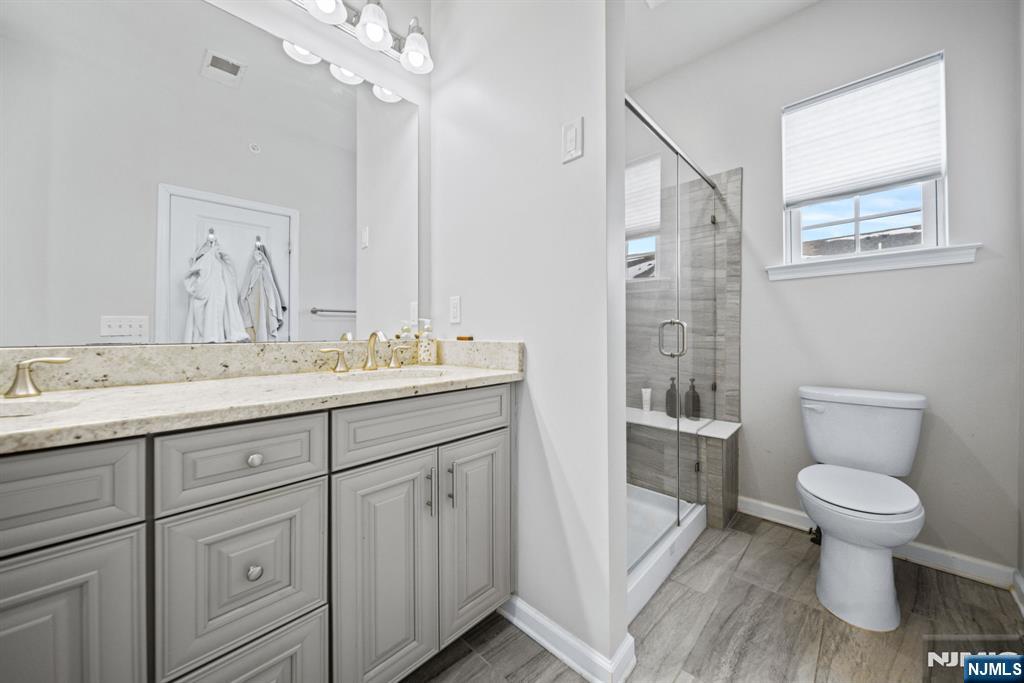84 Truman Drive, Unit 2801 Wood-Ridge, NJ 07075 - Photo 25 of 46 a bathroom with a granite countertop sink a toilet and a mirror