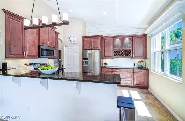 a kitchen with stainless steel appliances granite countertop a refrigerator a sink dishwasher a stove a dining table and chairs with wooden floor