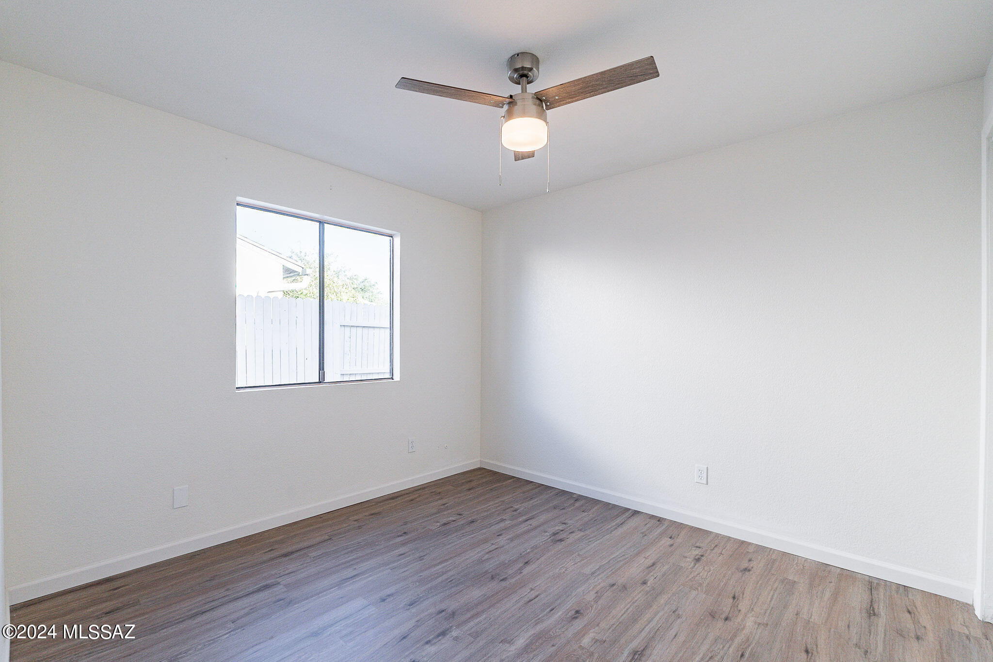 2690 West Sunset Road Tucson, AZ 85741 - Photo 18 of 33 an empty room with wooden floor and windows
