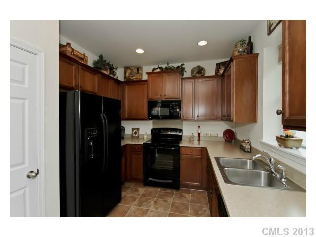 3342 Streamside Drive Davidson, NC 28036 - Photo 6 of 16 a kitchen with kitchen island granite countertop a refrigerator a sink and wooden cabinets