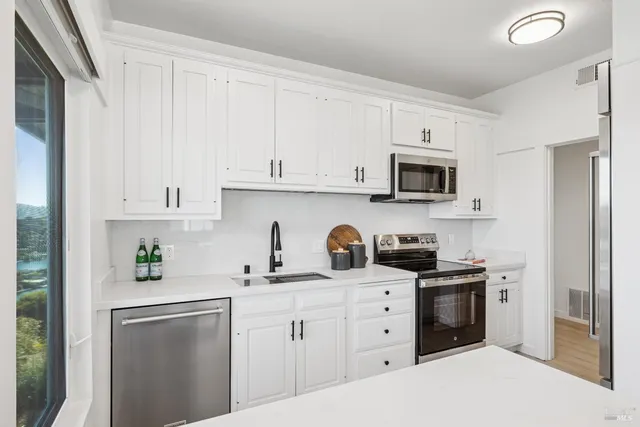 a kitchen with white cabinets and appliances