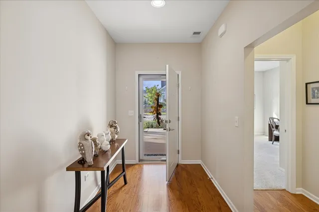 a view of a hallway with wooden floor and a livingroom
