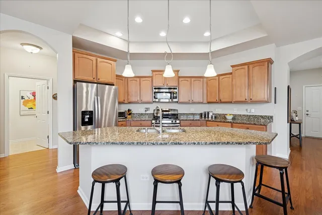 a kitchen with stainless steel appliances granite countertop a table chairs sink refrigerator and microwave