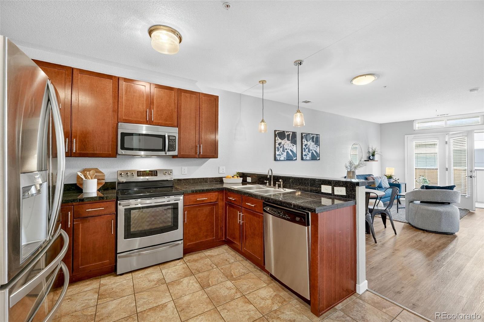 3101 Blake Street, Unit 209 Denver, CO 80205 - Photo 11 of 33 a kitchen with stainless steel appliances granite countertop a stove top oven a sink dishwasher a dining table and chairs