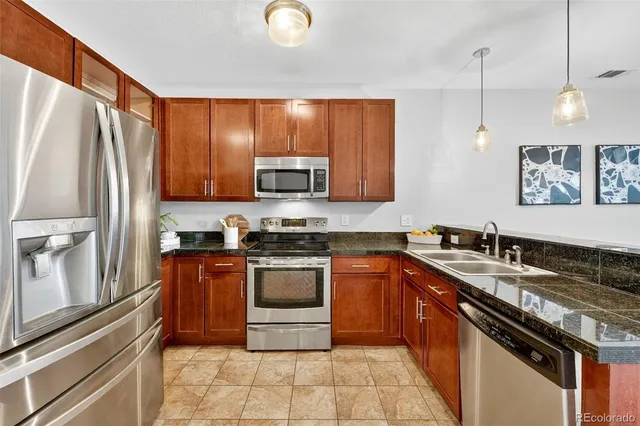 a kitchen with stainless steel appliances granite countertop a stove a sink dishwasher a refrigerator and a microwave