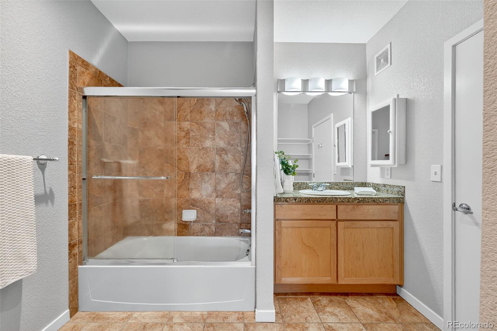 3101 Blake Street, Unit 209 Denver, CO 80205 - Photo 16 of 33 a bathroom with a granite countertop bathtub shower sink and mirror