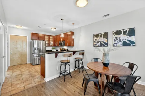 a kitchen with stainless steel appliances kitchen island granite countertop a dining table chairs refrigerator and sink