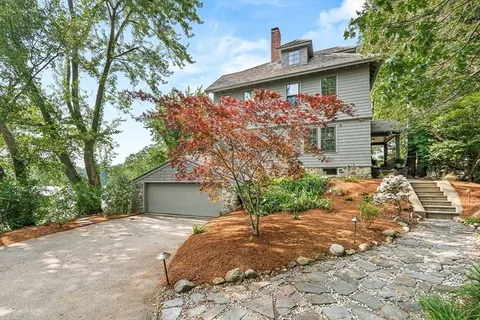 a view of a wooden house with a yard and large trees