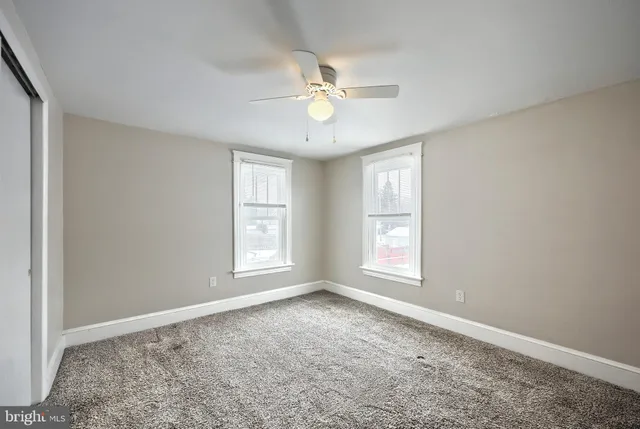 a view of empty room with window and ceiling fan