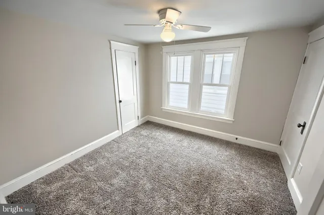 an empty room with windows and fan
