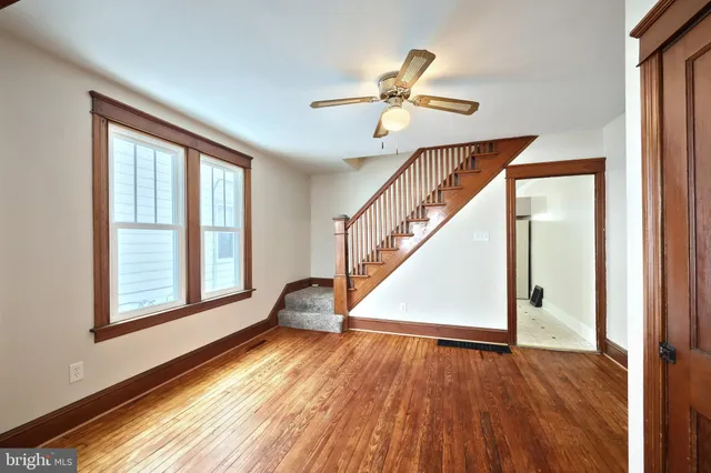 a view of empty room with wooden floor and fan