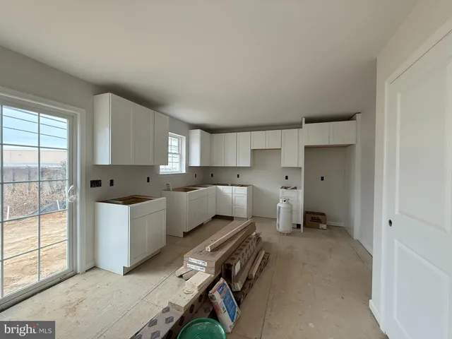 a large white kitchen with a refrigerator a stove a sink and white cabinets