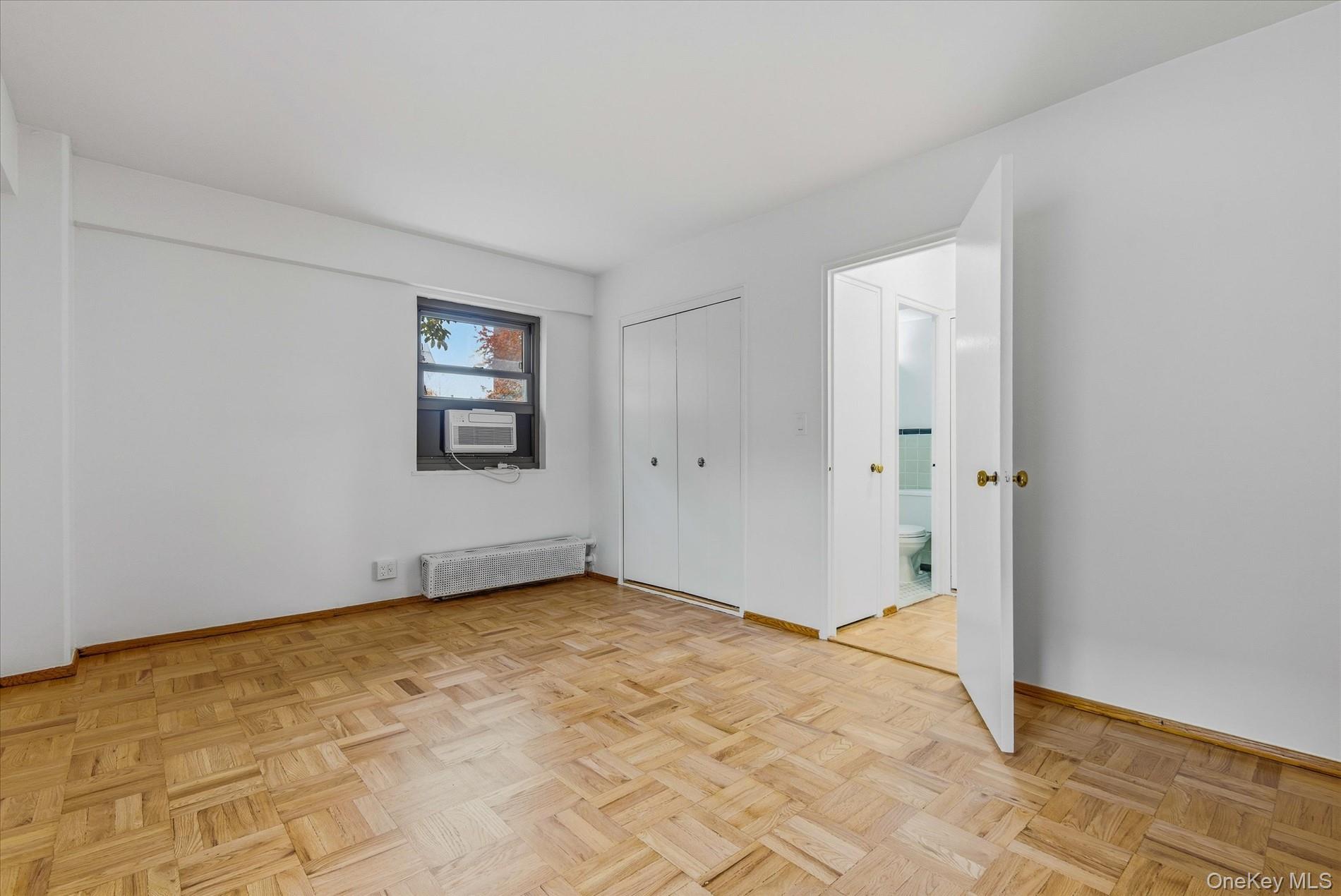 21-85 34th Avenue, Unit 2D Queens, NY 11106 - Photo 12 of 17 Unfurnished bedroom with radiator heating unit and a closet