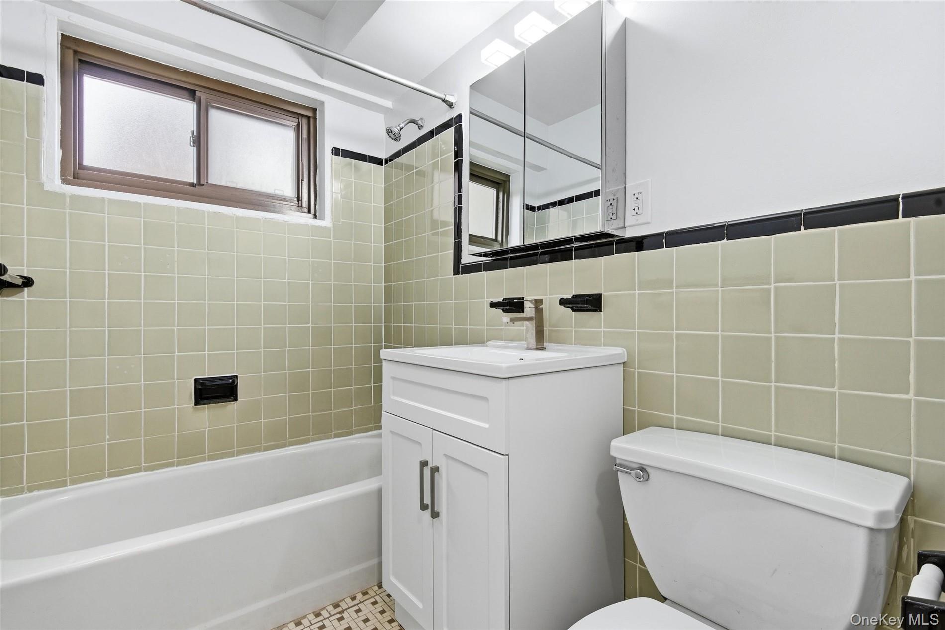 21-85 34th Avenue, Unit 2D Queens, NY 11106 - Photo 13 of 17 Bathroom with shower combination, vanity, and tile walls