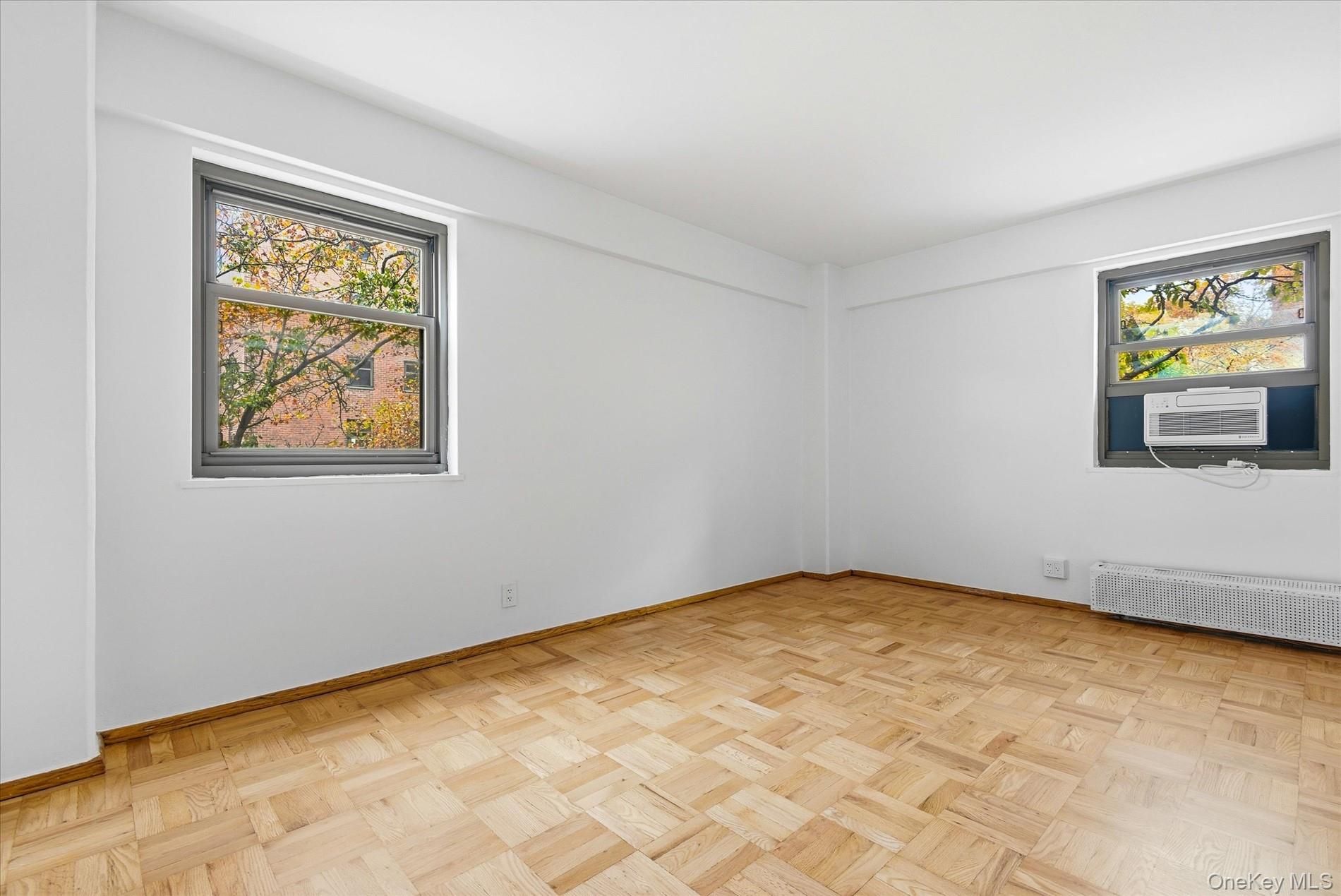 21-85 34th Avenue, Unit 2D Queens, NY 11106 - Photo 10 of 17 Empty room featuring radiator, plenty of natural light, and cooling unit