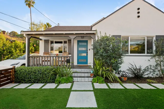 a view of a house with brick walls and a yard with plants