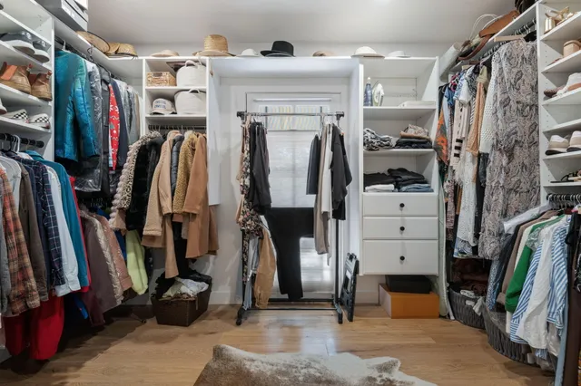 a view of walk in closet with clothes and shoes