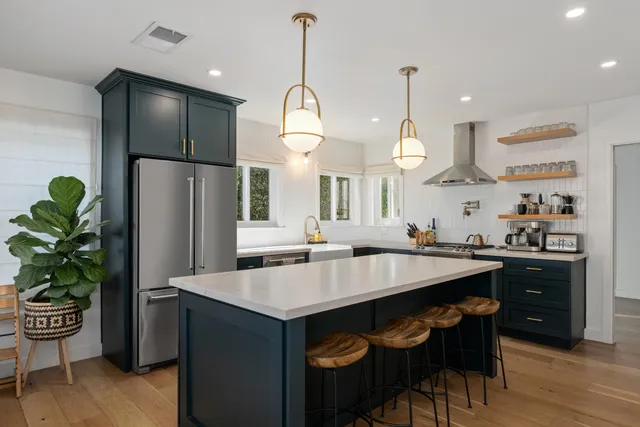 a kitchen with stainless steel appliances granite countertop a refrigerator a sink dishwasher a dining table and chairs with wooden floor