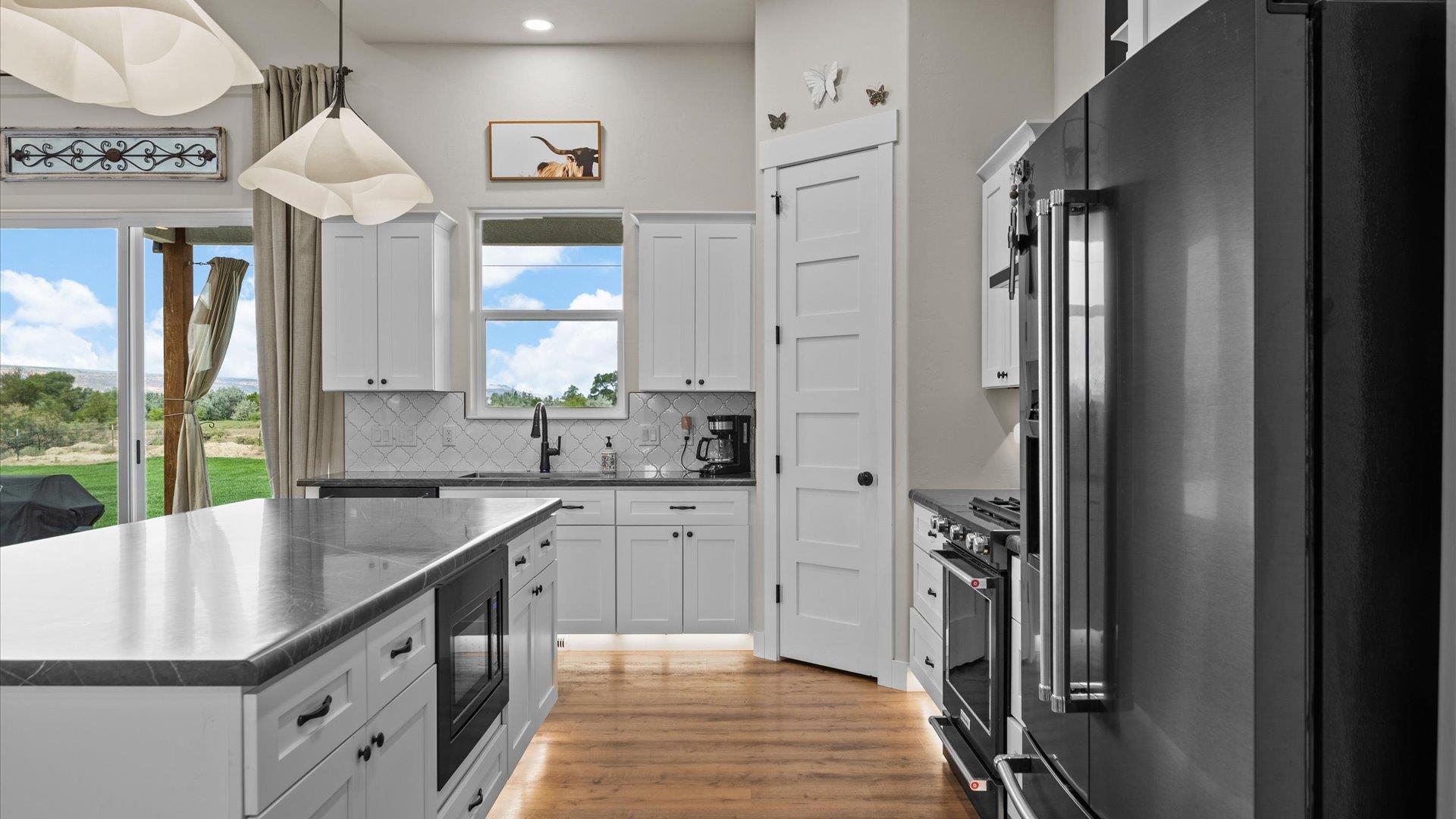 1730 Stremel Creek Fruita, CO 81521 - Photo 12 of 42 a kitchen with stainless steel appliances granite countertop a refrigerator a sink dishwasher a stove and a dining table with wooden floor
