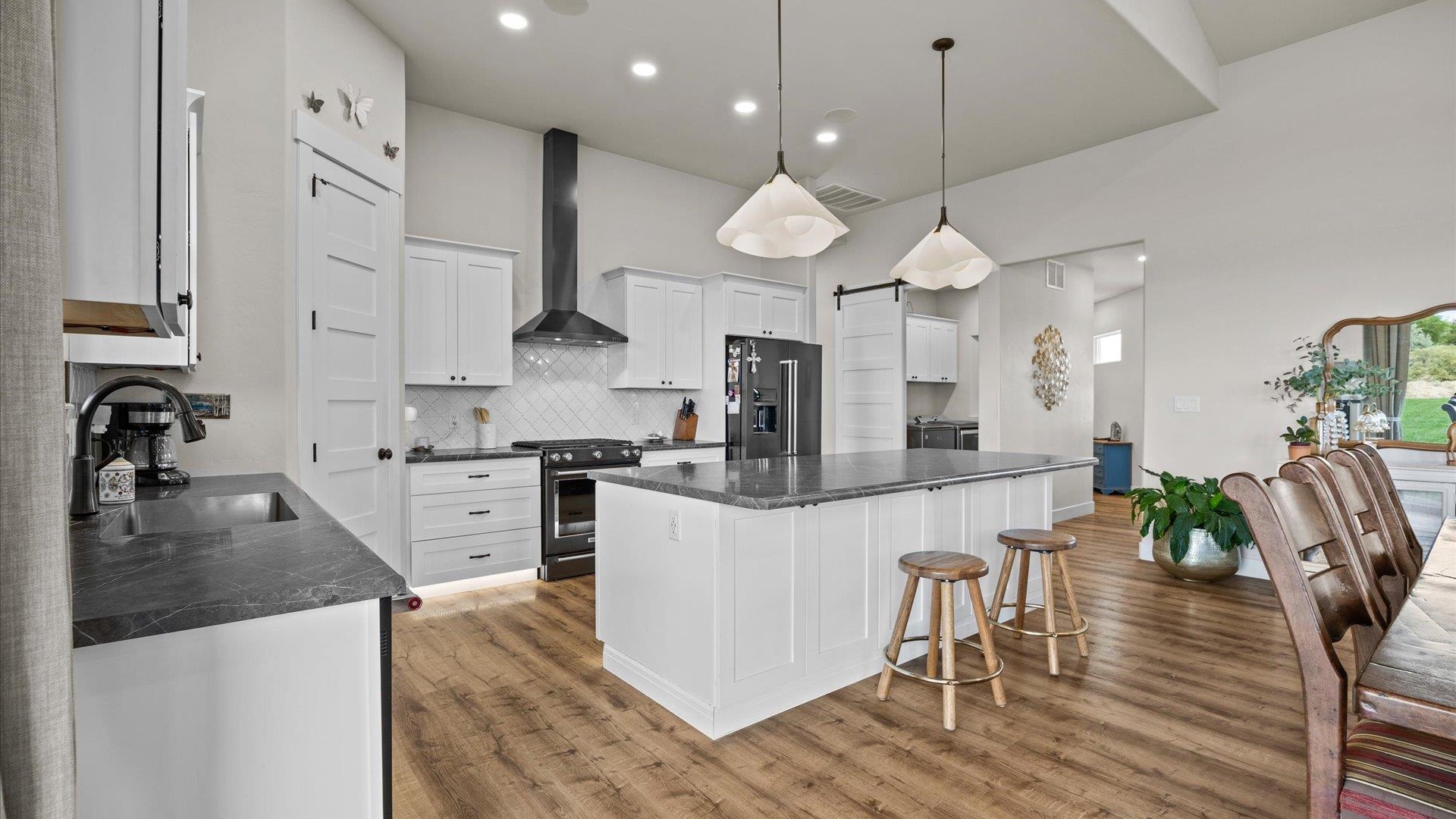1730 Stremel Creek Fruita, CO 81521 - Photo 14 of 42 a kitchen with stainless steel appliances kitchen island granite countertop a stove a sink a refrigerator and a dining table with wooden floor