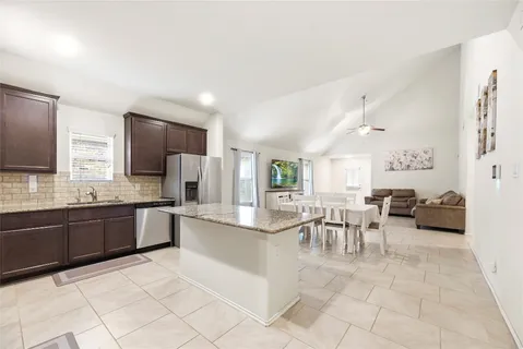 a large kitchen with stainless steel appliances granite countertop a stove top oven a sink and dishwasher