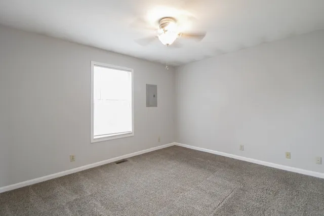 an empty room with a window and a fan