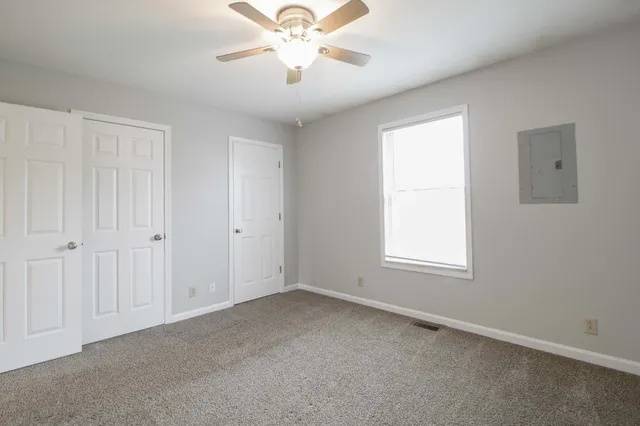 an empty room with windows and fan