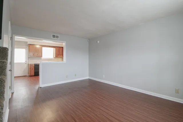 a view of an empty room with wooden floor and a window