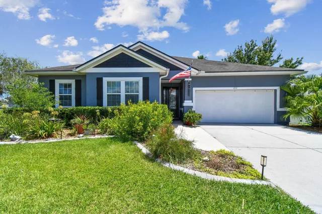 a front view of a house with a yard and potted plants