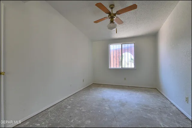 an empty room with a window and a fan