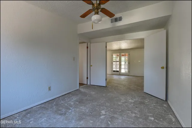 an empty room that has a window and a ceiling fan