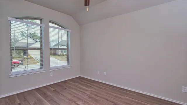an empty room with wooden floor and windows
