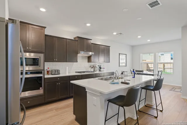 a kitchen with a sink stainless steel appliances and chairs