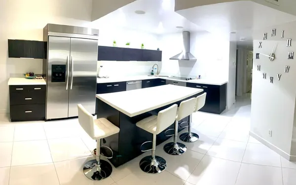 a kitchen with stainless steel appliances kitchen island granite countertop a refrigerator a stove a sink and a oven